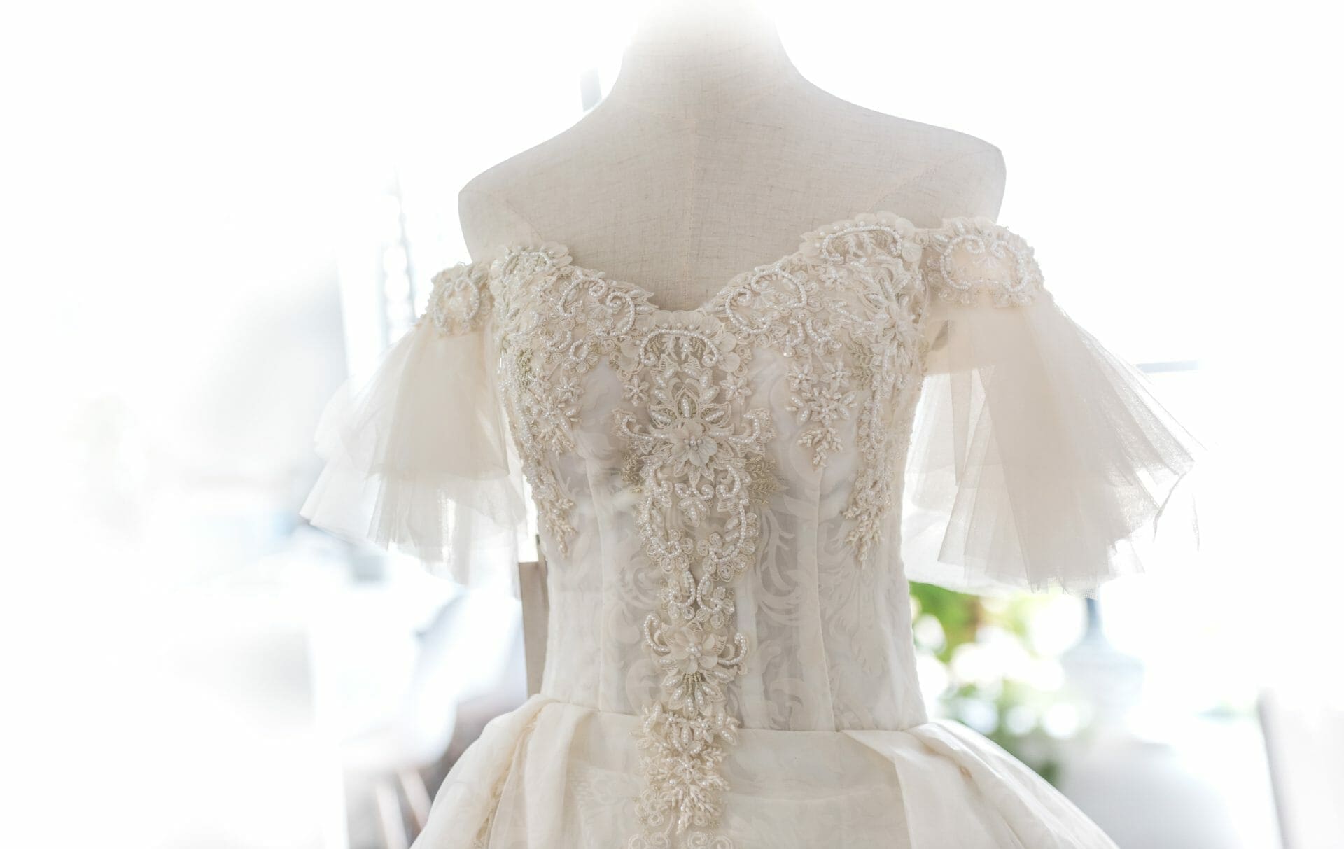 An off the shoulder wedding dress on a mannequin.