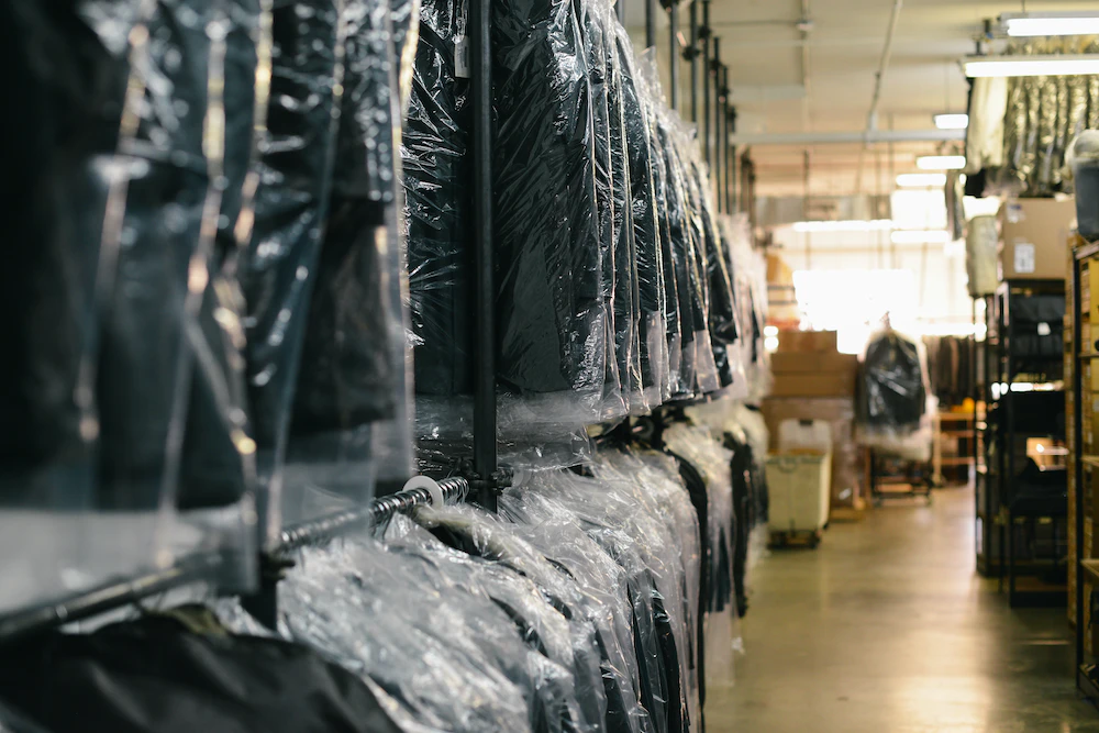 A warehouse with a lot of clothes hanging on racks.