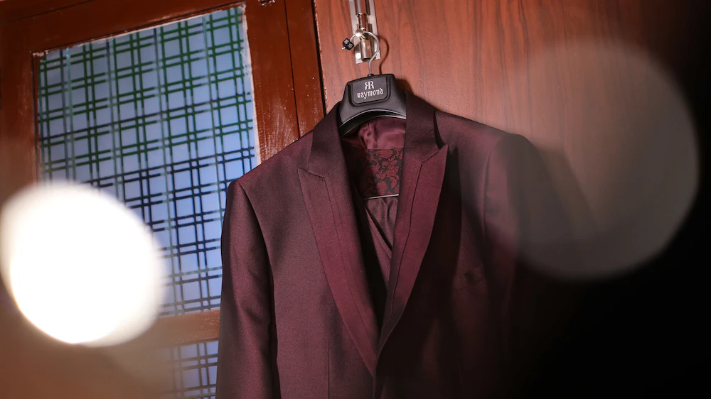 A burgundy suit hanging on a hanger, ready for dry cleaning.