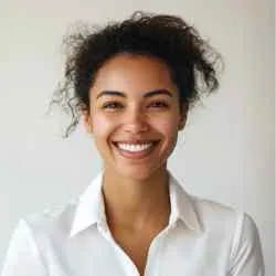 A woman with curly hair wearing a white collared shirt smiles at the camera against a plain background.